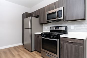 A kitchen with a stainless steel refrigerator, microwave, oven, and stove.
